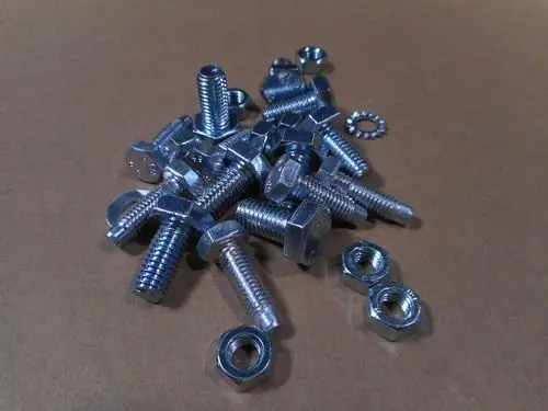 Verschiedene Befestigungselemente wie Schrauben und Unterlegscheiben aus Metall, angeordnet auf einem braunen Hintergrund, ähnlich den Produkten von Remeha.